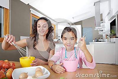 Mother and Daughter Beating Eggs in Kitchen Stock Photo