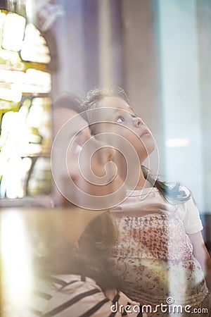 Mother and daughter in a church prying in a catechism education session. Christianity and catholicism concept and empty copy space Stock Photo