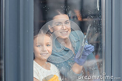 Mother and daughter cleaning window and smiling at camera Stock Photo