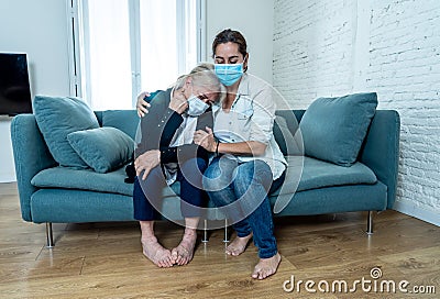 Mother and daughter crying at home in quarantine grieving loss of family members amid COVID-19 Stock Photo