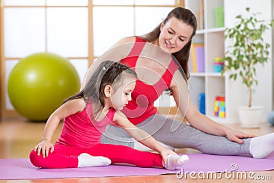 Mother and daughter doing fitness exercises on mat at home Stock Photo