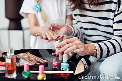 Mother and daughter doing manicure at home, painting nails with nail polish Stock Photo
