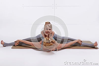 Mother daughter doing yoga exercise,fitness family sports, sports paired woman sitting on the floor stretching his legs apart in Stock Photo