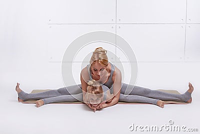 Mother daughter doing yoga exercise,fitness family sports, sports paired woman sitting on the floor stretching his legs apart in Stock Photo