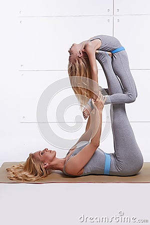 Mother daughter doing yoga exercise fitness gym wearing the same comfortable tracksuits family sports paired woman lies on back li Stock Photo