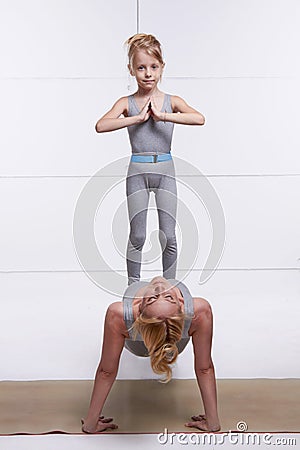 Mother and daughter doing yoga exercise, fitness, gym wearing the same comfortable tracksuits family sports paired woman p Stock Photo