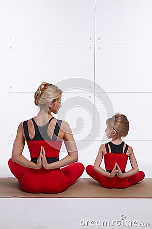 Mother daughter doing yoga exercise, fitness, gym wearing the same comfortable tracksuits, family sports, sports paired Stock Photo