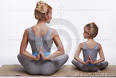 Mother daughter doing yoga exercise, fitness, gym wearing the same comfortable tracksuits, family sports, sports paired Stock Photo