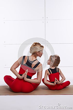Mother daughter doing yoga exercise, fitness, gym wearing the same comfortable tracksuits, family sports, sports paired Stock Photo
