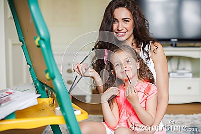 Mother and daughter drawing in the room. Stock Photo