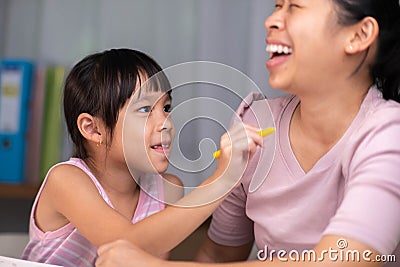 Mother and daughter drawing together with crayons. Adult woman helps girl study or draw together at home in living room. Happy Stock Photo