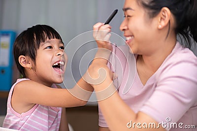 Mother and daughter drawing together with crayons. Adult woman helps girl study or draw together at home in living room. Happy Stock Photo