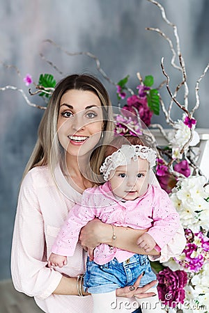 Mother and daughter embrace. Beautiful woman with kid girl. Studio portrait with flowers. Female model. Stock Photo