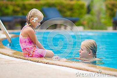 Mother and daughter with flower behind ear have fun at pool side Stock Photo