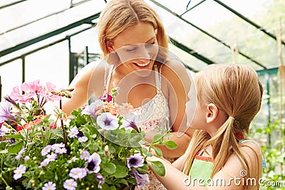 Mother And Daughter Growing Plants In Greenhouse Stock Photo