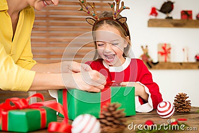Mother and daughter having fun wrapping christmas gifts together in living room. Candid family christmas time lifestyle. Stock Photo