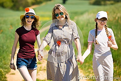 Mother with daughter having poppy flowers are walking on cart road Stock Photo