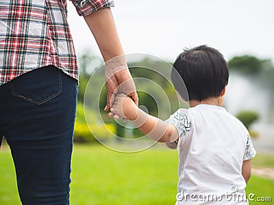 Mother and daughter holding hands walking in the park. Kid and M Stock Photo