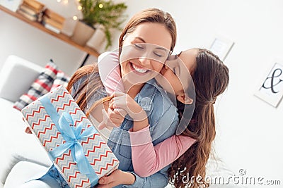 Mother and daughter at home mother`s day sitting daughter hugging mom holding present kissing Stock Photo