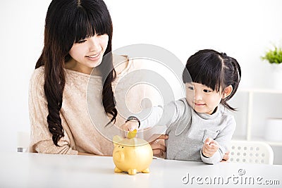 mother and daughter Inserting Coin In Piggy bank Stock Photo