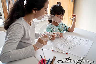 Mother and daughter learning to read and write letter at home Stock Photo