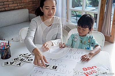 Mother and daughter learning to read and write letter at home Stock Photo