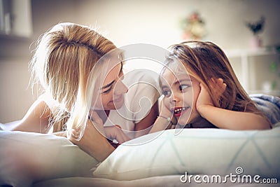 Mother and daughter lying on a bed, morning time. Stock Photo