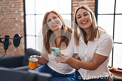 Mother and daughter musicians using smartphone drinking coffee at music studio Stock Photo