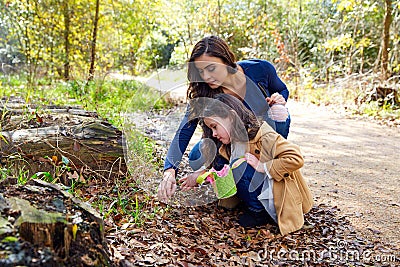 Mother daughter in a park picking clover plants Stock Photo