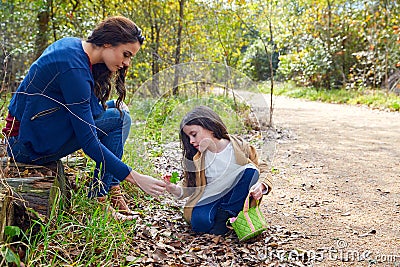 Mother daughter in a park picking clover plants Stock Photo