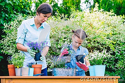 Mother and daughter planting flowers in pots in the garden Stock Photo