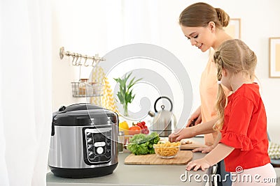 Mother and daughter preparing food near modern multi cooker Stock Photo