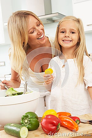 Mother & Daughter Preparing Salad In Kitchen Stock Photo