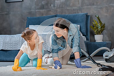 Mother and daughter in protective gloves cleaning carpet Stock Photo