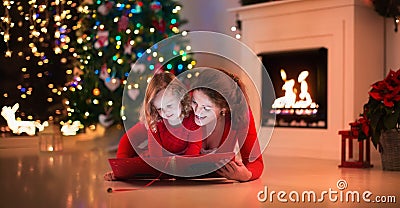 Mother and daughter read a book at fireplace on Christmas eve. Stock Photo