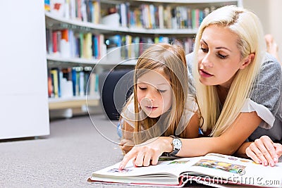 Mother with daughter read book together in library Stock Photo