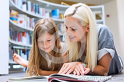 Mother with daughter read book together in library Stock Photo