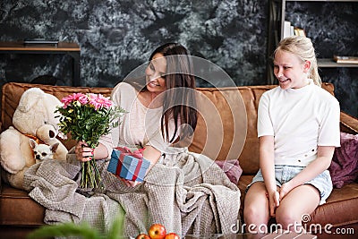 Mother and daughter relationship concept. A teenage girl congratulates happy woman on her birthday and gives her Stock Photo