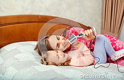 Mother and daughter sing fun together karaoke songs in the room. Stock Photo