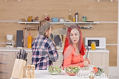 Mother and daughter singing on kitchen intruments Stock Photo