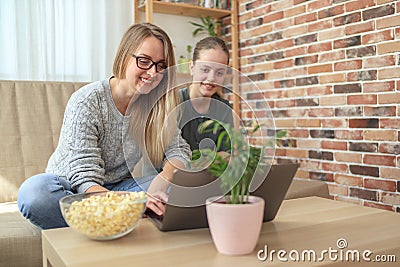 Mother with daughter sitting on sofa and watching series Stock Photo