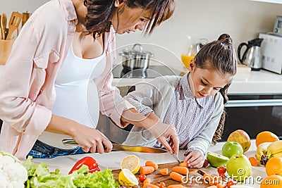 mother with daughter slicing carrots on chopping board Stock Photo