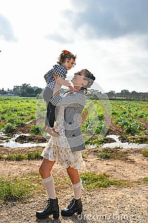 Mother and daughter standing in a vast meadow, the woman cradling the little girl in her arms. Stock Photo