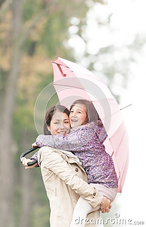 Mother and daughter under umbrella in autumn. Stock Photo