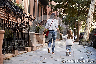 Mother and daughter walking down the street, back view Stock Photo