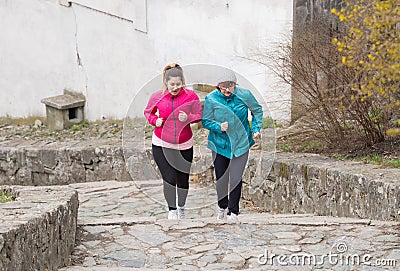 Mother and daughter wearing sportswear and running upstairs at c Stock Photo