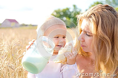 Mother and daughter in wheat field. Happy Family outdoors. healthy child with mother on picnic with bread and milk in golden Stock Photo