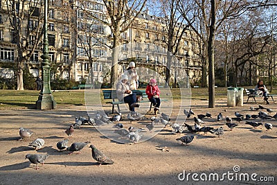 Mother and daughters feeding pigeons Editorial Stock Photo
