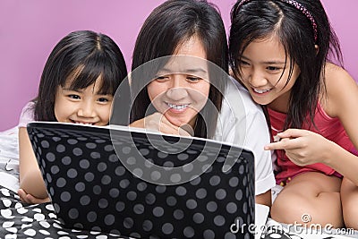 Mother and daughters playing with laptop Stock Photo