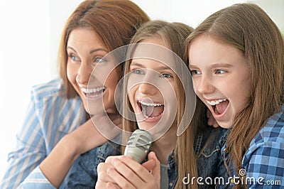 Mother and daughters singing karaoke Stock Photo